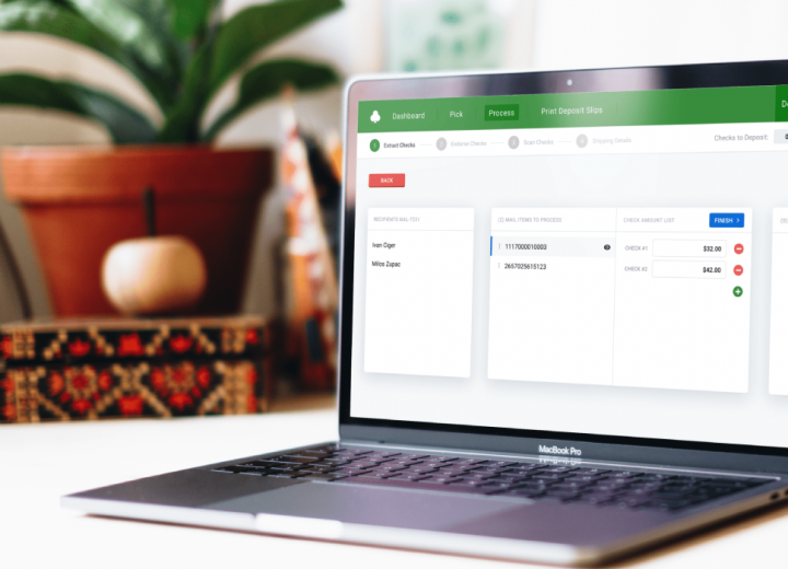 A laptop displaying a section of an app developed for a client, with the main menu listed on the top of the screen and opened "Extract Checks" tab. The laptop is placed on the desk, with the desk-flower, pictures...behind it.